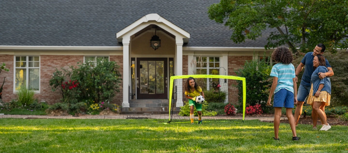 family playing soccer in the front yard