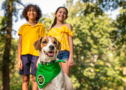 Two kids standing with dog.