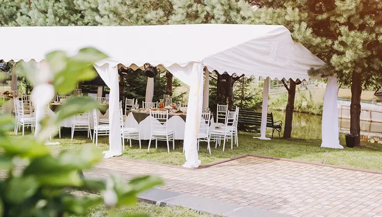 A picture of a white canopy tent with tables set under it.