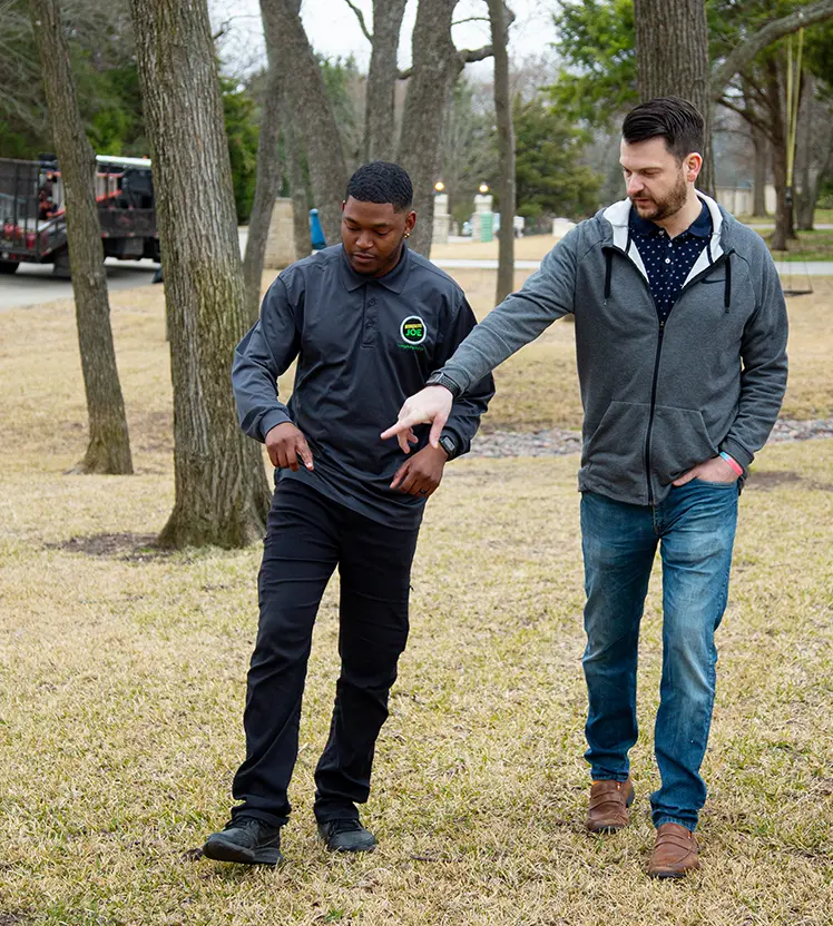 Two Mosquito Joe technicians walking and pointing at a customer's yard.