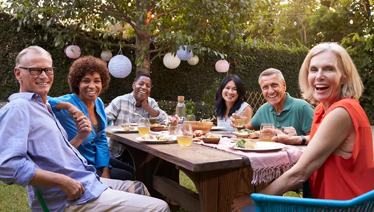 Picture of a group sitting at a table outside enjoying a party.