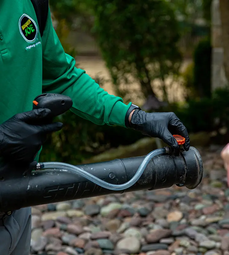 A closeup of a Mosquito Joe technician spraying a customer's yard.