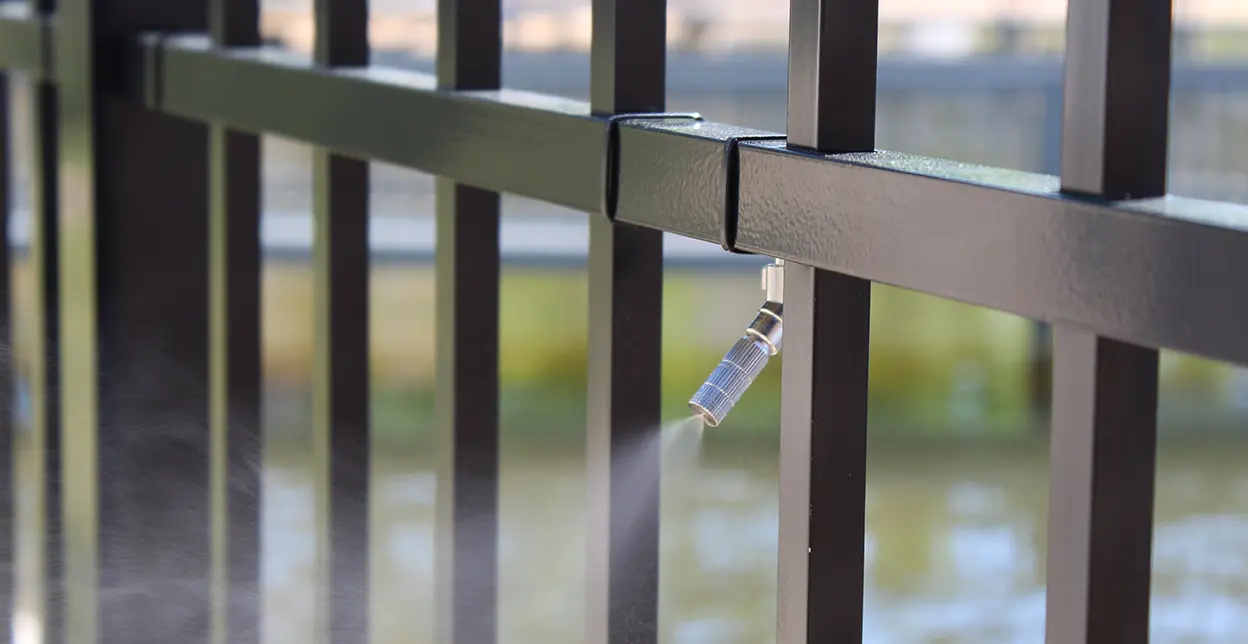 A picture of a mosquito misting system attached to a fence.