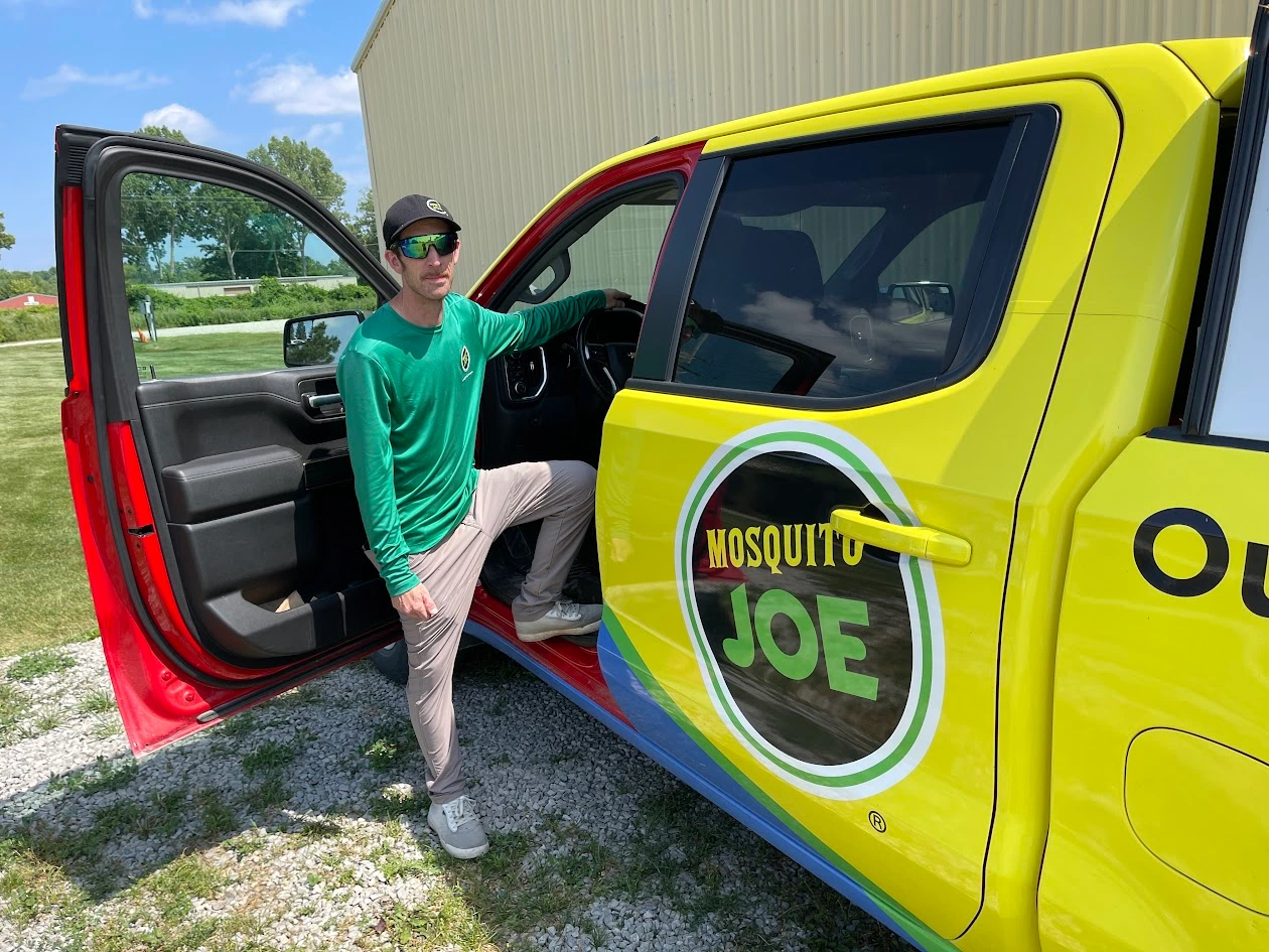 Mosquito Joe of Ann Arbor service professional posing beside a Mosquito Joe service truck