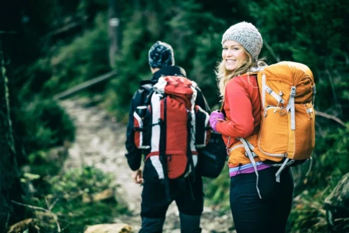 man and woman hikers trekking through the woods 