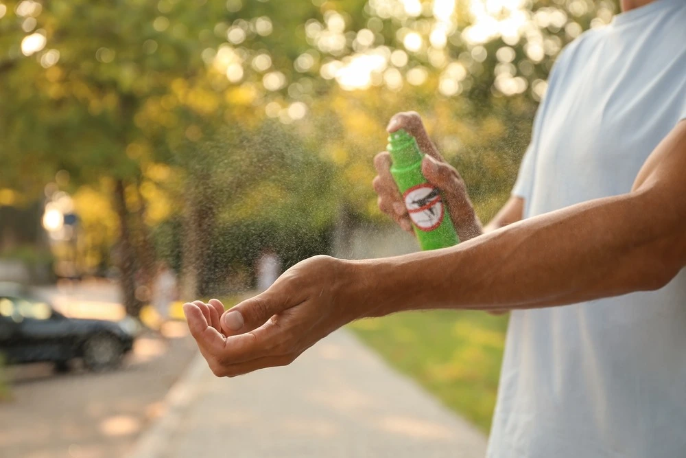 Person spraying mosquito spray on the arm.